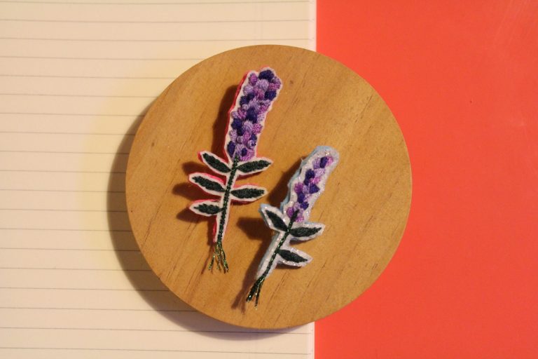 broderie qui représente deux fleurs violettes de type lavande.